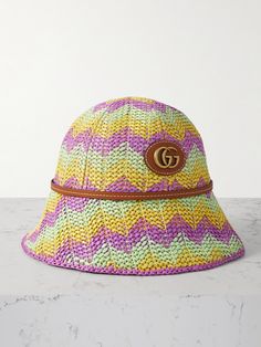 Gucci's bucket hat is made from pastel-colored straw that's woven to create chevron stripes, ensuring it will add a splash of fun to your warm-weather wardrobe. It's lined in soft twill for a comfortable fit and has brown leather trims. Match your jewelry to the gold-tone 'GG' logo embellishment. Gucci Short Brim Summer Hats, Gucci Adjustable Bucket Hat, Spring Straw Bucket Hat, Gucci Adjustable Brimmed Hat, Designer Brimmed Beach Hats, Designer Spring Bucket Hat With Short Brim, Designer Beach Hat With Curved Brim, Woven Summer Bucket Hat, Designer Beach Hats For Spring