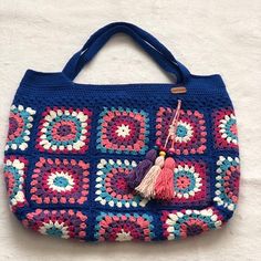 a blue crocheted purse with a tasseled handle and colorful circles on it