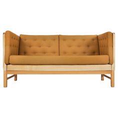 a tan and white couch sitting on top of a wooden frame with an armrest