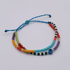 multicolored beaded bracelets with evil eye charm on white background, closeup