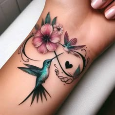 a hummingbird with flowers on its arm and heart in the middle is sitting next to a pink flower