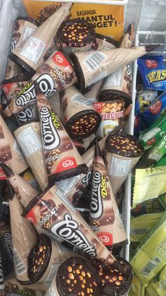 a pile of chocolate covered candy bars sitting on top of a white bin filled with other snacks