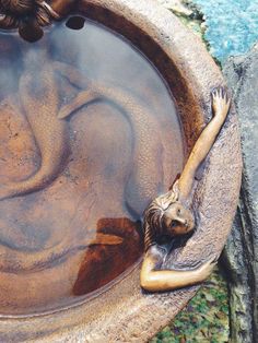 a statue is in the water with its arms stretched out and it's head resting on her back