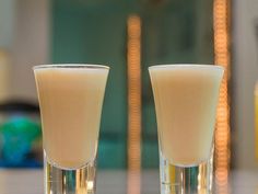 two glasses filled with liquid sitting on top of a table next to eachother