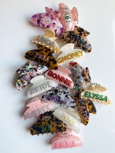 several different types of hair clips on a white surface with words written on them and flowers in the middle