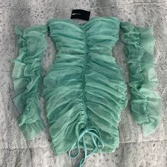 a piece of clothing laying on top of a bed covered in green fabric and ruffles