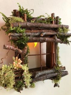 a birdhouse made out of branches with moss growing on the roof and window frame