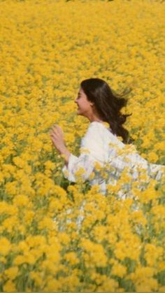 a woman sitting in a field of yellow flowers