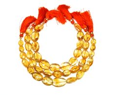 three strands of yellow glass beads with orange tassels