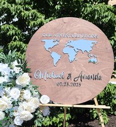 a wooden sign that says our adventure begins with the world map on it and flowers