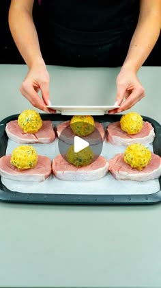 a person is preparing food on a tray with chopsticks and a video screen