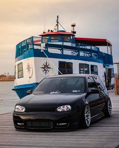 a black car is parked next to a boat