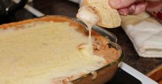 a person dipping some food into a casserole