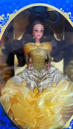 the doll is wearing a yellow dress with gold trimmings and a tiara