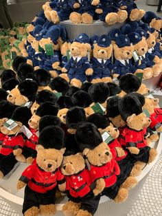 many teddy bears are dressed in red, black and blue uniforms on a round table