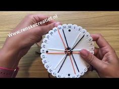 two hands are holding a clock made out of paper