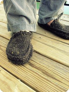 a person standing on top of a wooden deck next to a pair of feet wearing slippers