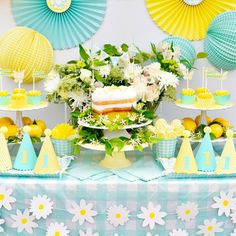 a table topped with cake and cupcakes covered in frosting next to paper fans