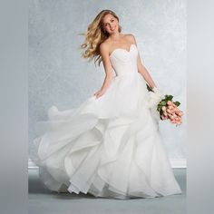 a woman in a white wedding dress holding a bouquet and posing for the camera with her long blonde hair