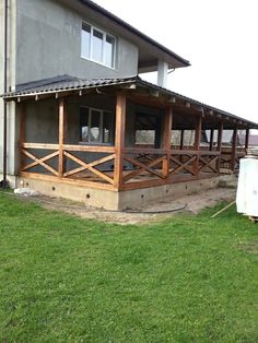 a house that has some grass in front of it and a fence around the porch