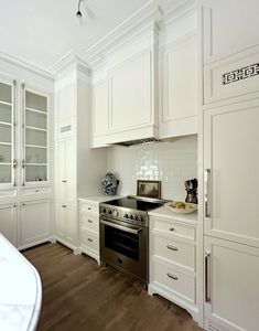 a kitchen with white cabinets and stainless steel stove top oven in the center of the room