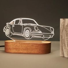 a car shaped lamp on top of a wooden stand next to a piece of wood