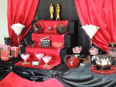 red and black dessert table with candy bars, candies, popcorn buckets and oscar awards decorations