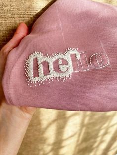 someone is holding a pink beanie with beading on the front and back side