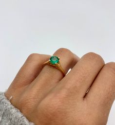 a woman's hand with a green ring on top of her finger and an emerald stone in the middle