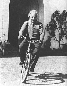 an old black and white photo of a man riding a bike