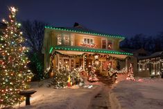 a house covered in christmas lights and decorated for the holiday season with a tree on the front porch