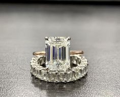 an emerald - cut diamond ring with baguets and side stones is displayed on a table