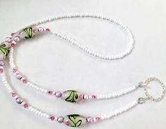 This is my best selling white lampworked beaded eyeglass necklace, it is done with 4 beautiful pink flowered swirls with green accents on white. it is accented with pink austrian crystals and faceted glass accents, it is strung with white  czech glass beads and is finished with a silverplated loop to hang those glasses and sunglasses arms thru. useful yet pretty enough for a necklace.it is approx 28" total around. this retails in boutiques that i sell to for $48. you are getting it at my wholesa Handmade White Necklaces For Spring, White Adjustable Beaded Necklace With Lobster Clasp, White Czech Glass Necklaces As Gift, Adjustable White Beaded Necklace With Lobster Clasp, White Single Strand Glass Necklace, White Glass Beaded Necklaces For Gifts, White Czech Glass Necklace With Adjustable Fit, White Czech Glass Jewelry For Gift, Pastel Pink Flowers