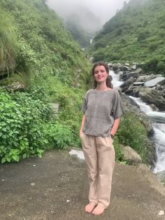 a woman standing on top of a hill next to a river