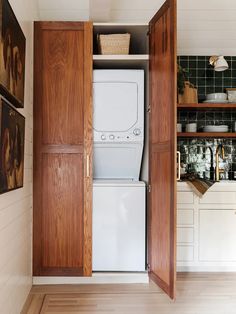 a washer and dryer sitting inside of a wooden cabinet in a small kitchen