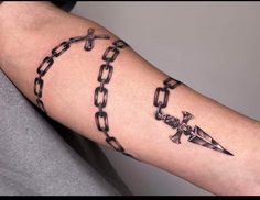 a man's arm with chains and cross tattoos on it