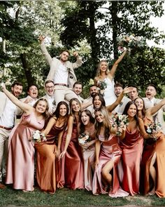 a group of people standing next to each other posing for a photo in front of trees