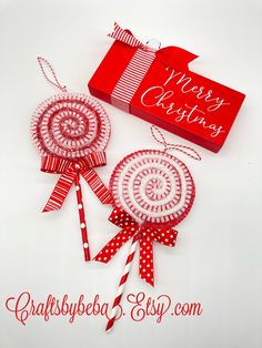 two red and white lollipops are next to a christmas card