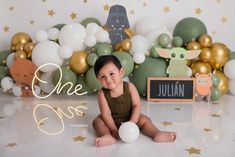 a baby is sitting on the floor in front of balloons and star garlands while smiling at the camera