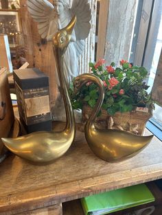 two brass swan planters sitting on top of a wooden table