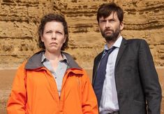 a man and woman standing next to each other in front of a rocky cliff face