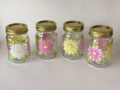 four glass jars with painted flowers on them