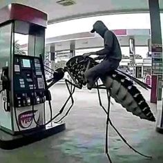 the man is trying to get gas from the machine at the gas station and he's getting ready to jump