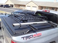 a truck with a rack on the back of it's bed in front of some houses