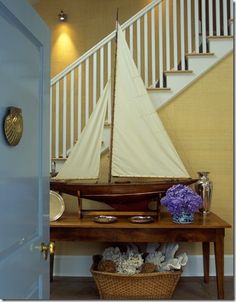 a sailboat sitting on top of a wooden table next to a stair case in a house