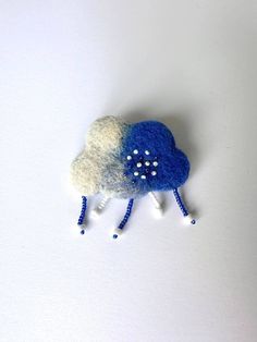 a blue and white sheep brooch with pearls on it's head, sitting on a white surface