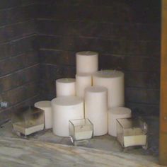 several white candles sitting on the floor next to each other in front of a brick wall