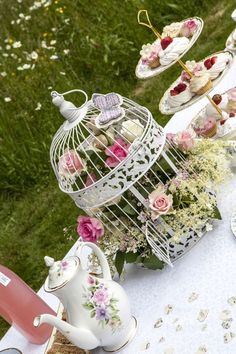 a table topped with lots of cakes and cupcakes next to a birdcage