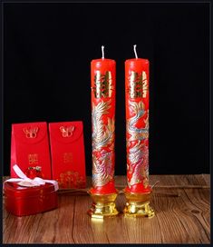 two red candles sitting on top of a wooden table next to boxes and a box