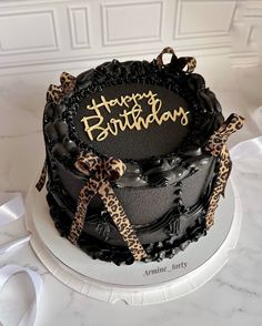 a black and gold birthday cake with leopard print ribbon